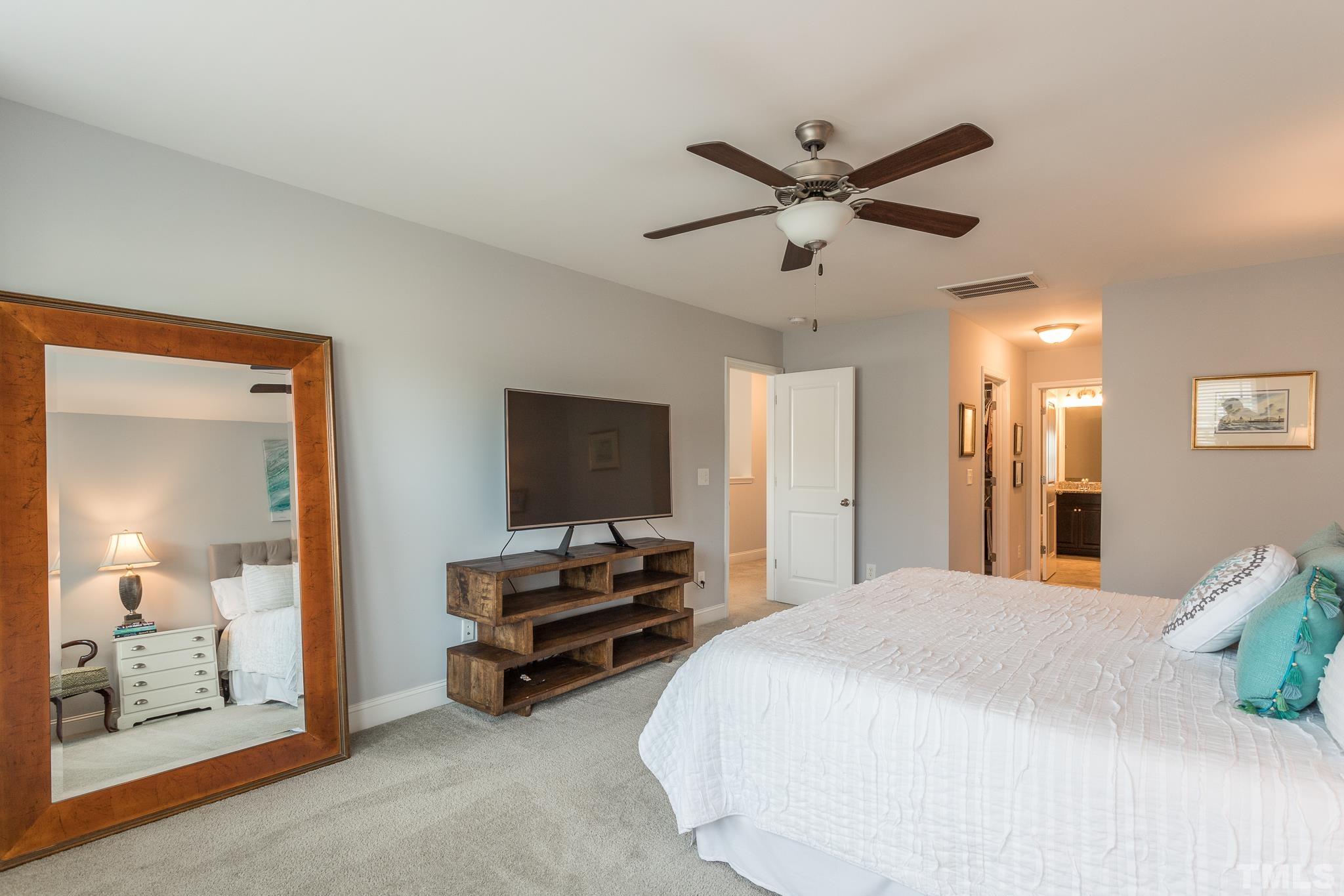 114 Willow View Lane Apex, NC 27539 - Photo 20 of 40 a spacious bedroom with a bed and a chandelier