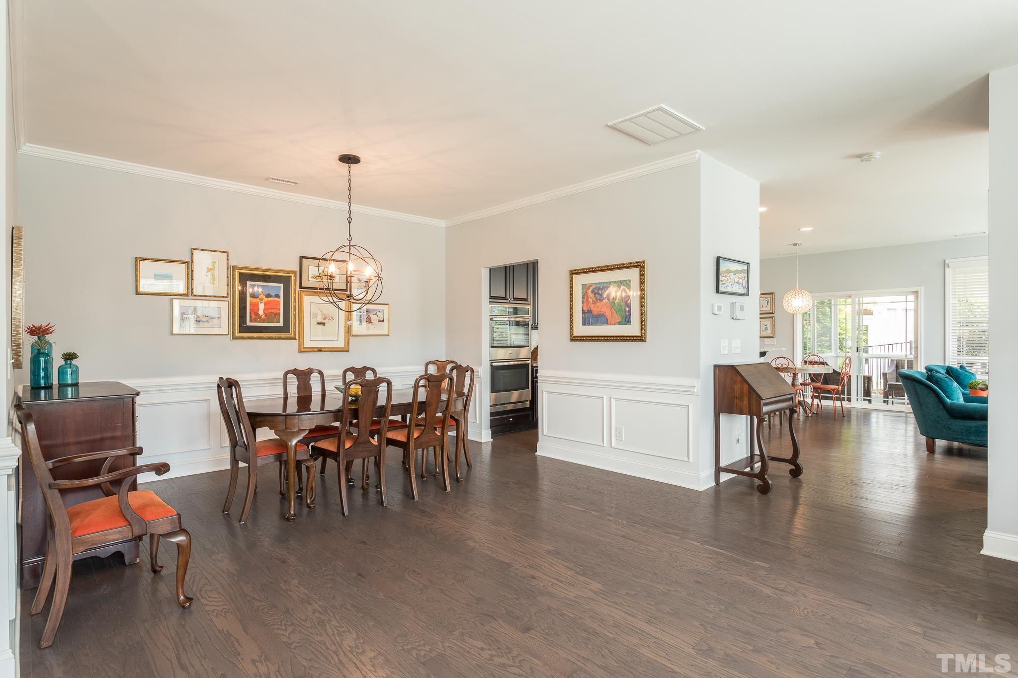 114 Willow View Lane Apex, NC 27539 - Photo 7 of 40 a dining room with wooden floor a chandelier a wooden table and chairs