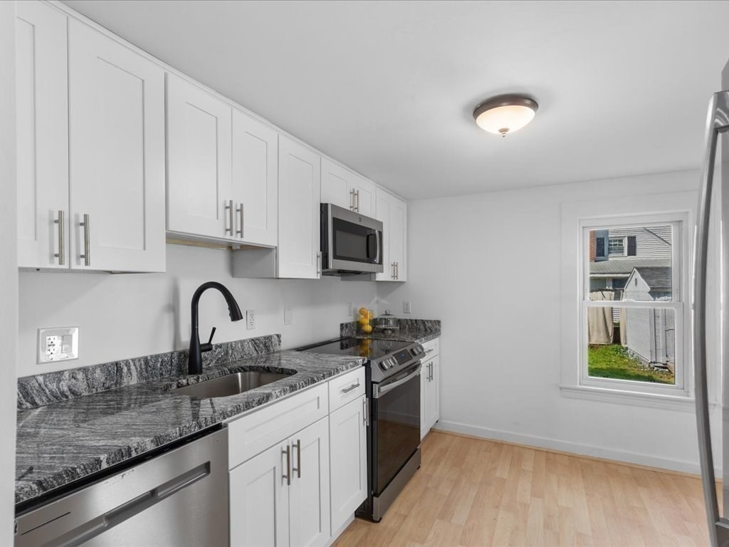 21 Ellis Street Framingham, MA 01701 - Photo 14 of 40 a kitchen with stainless steel appliances granite countertop a sink a stove a microwave a refrigerator a counter space and cabinets