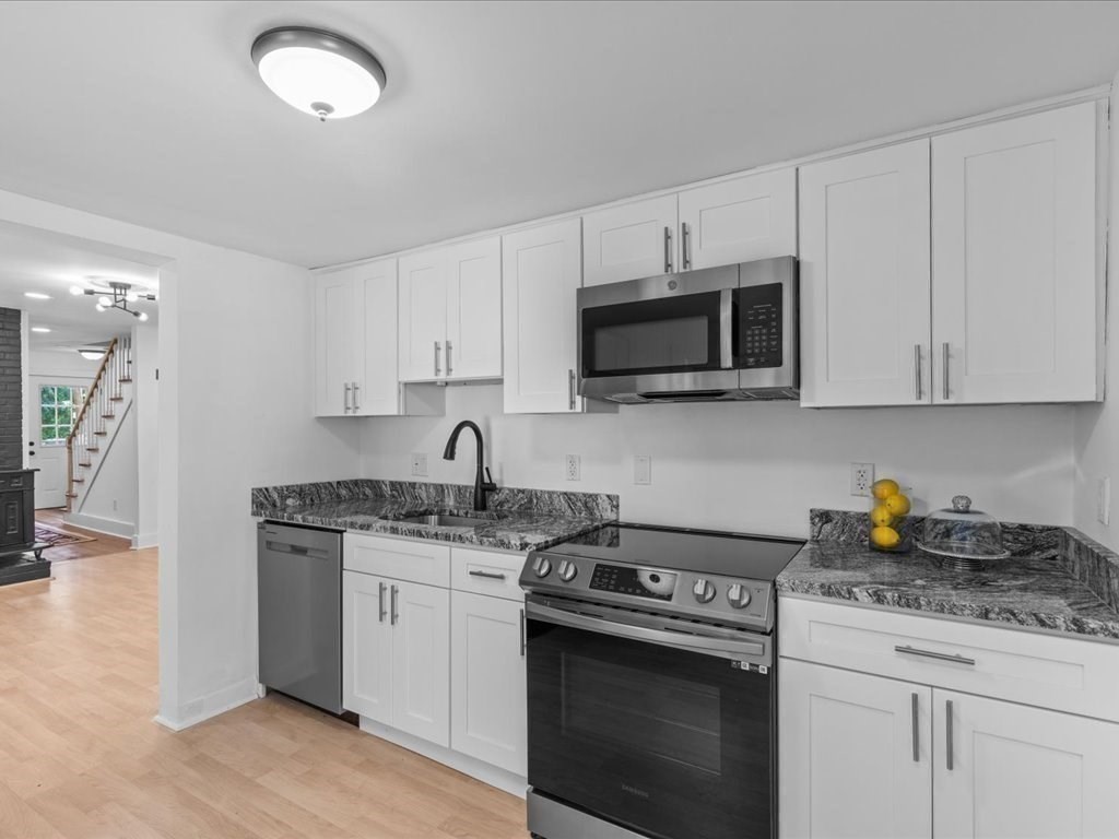 21 Ellis Street Framingham, MA 01701 - Photo 16 of 40 a kitchen with stainless steel appliances granite countertop a sink a stove a microwave and wooden cabinets