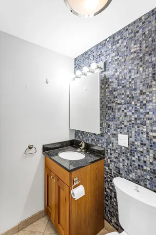 a bathroom with a granite countertop sink and a toilet