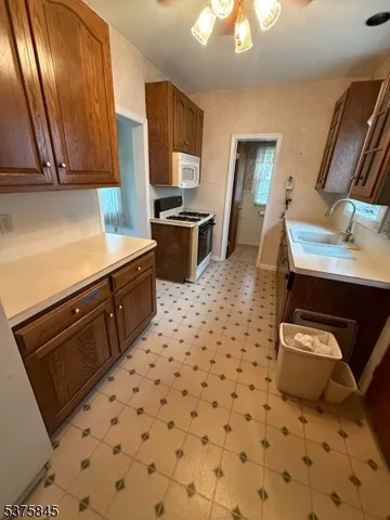 a kitchen with granite countertop a sink a stove a microwave oven with cabinets