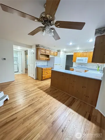 a kitchen with stainless steel appliances kitchen island granite countertop a sink cabinets and wooden floor