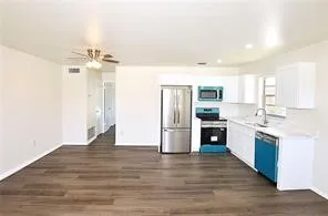 a large kitchen with cabinets wooden floor and stainless steel appliances