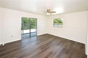 an empty room with wooden floor chandelier fan and windows