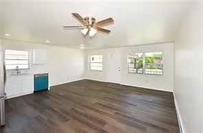 an empty room with wooden floor fan and windows