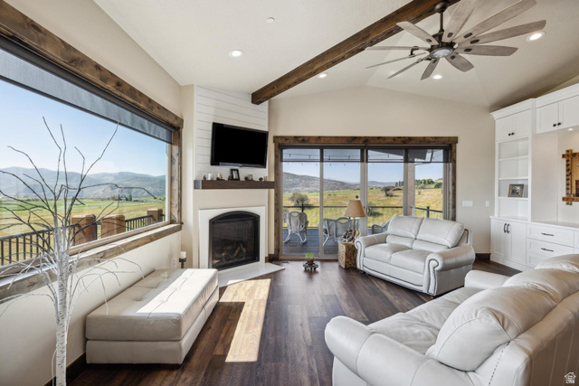6117 North Rocky Ridge Road Peoa, UT 84061 - Photo 38 of 82 Spacious living area featuring large picture windows, a fireplace with a mantel, vaulted ceilings with exposed wood beams, a ceiling fan, and built-in cabinetry