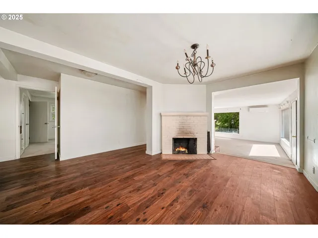 a view of empty room with fireplace and wooden floor
