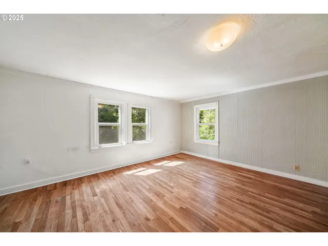 a view of an empty room with a window and wooden floor