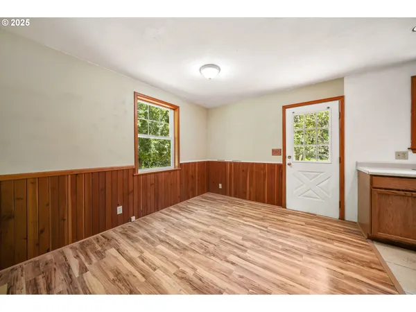 a view of an empty room with wooden floor and a window