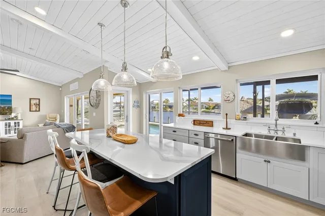 a kitchen with stainless steel appliances granite countertop a stove a sink dishwasher and white cabinets with wooden floor