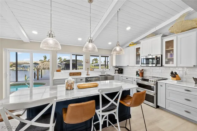 a kitchen with stainless steel appliances kitchen island granite countertop a table chairs and a view of living room