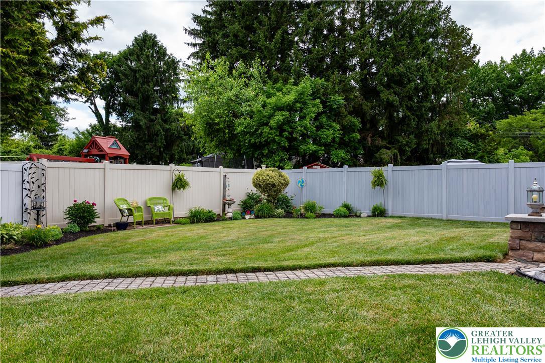 2087 Hopewell Road Bethlehem, PA 18017 - Photo 33 of 38 A neatly manicured lawn features a privacy fence and garden beds under a lush tree canopy.