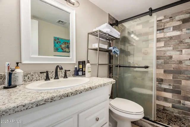 a bathroom with a granite countertop sink mirror vanity and toilet