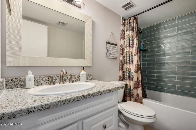 a bathroom with a granite countertop sink toilet mirror and shower