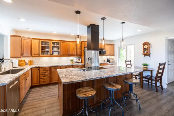 a kitchen with stainless steel appliances granite countertop a sink a stove and a wooden floors