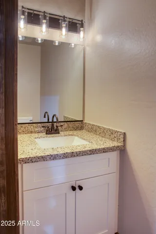a bathroom with a granite countertop sink and a mirror