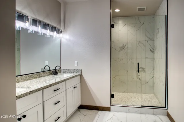 a bathroom with a granite countertop sink a mirror and shower