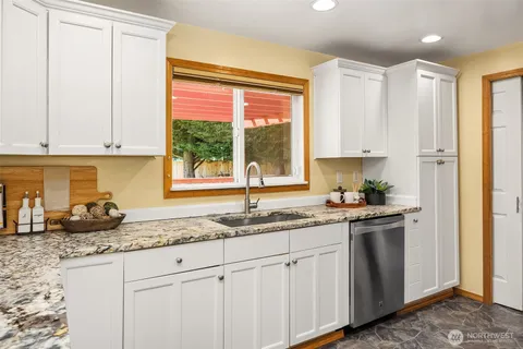 a kitchen with stainless steel appliances granite countertop a sink a stove and a window