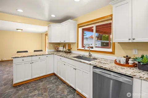 a kitchen with granite countertop a sink and white cabinets