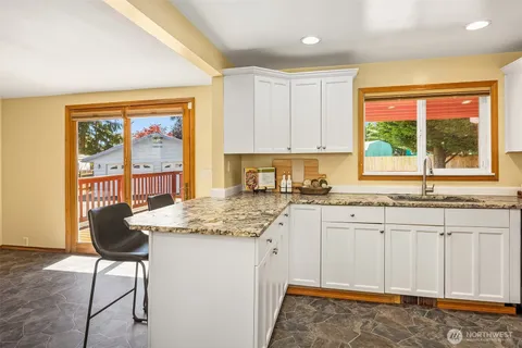 a kitchen with granite countertop a stove a sink and a wooden cabinets