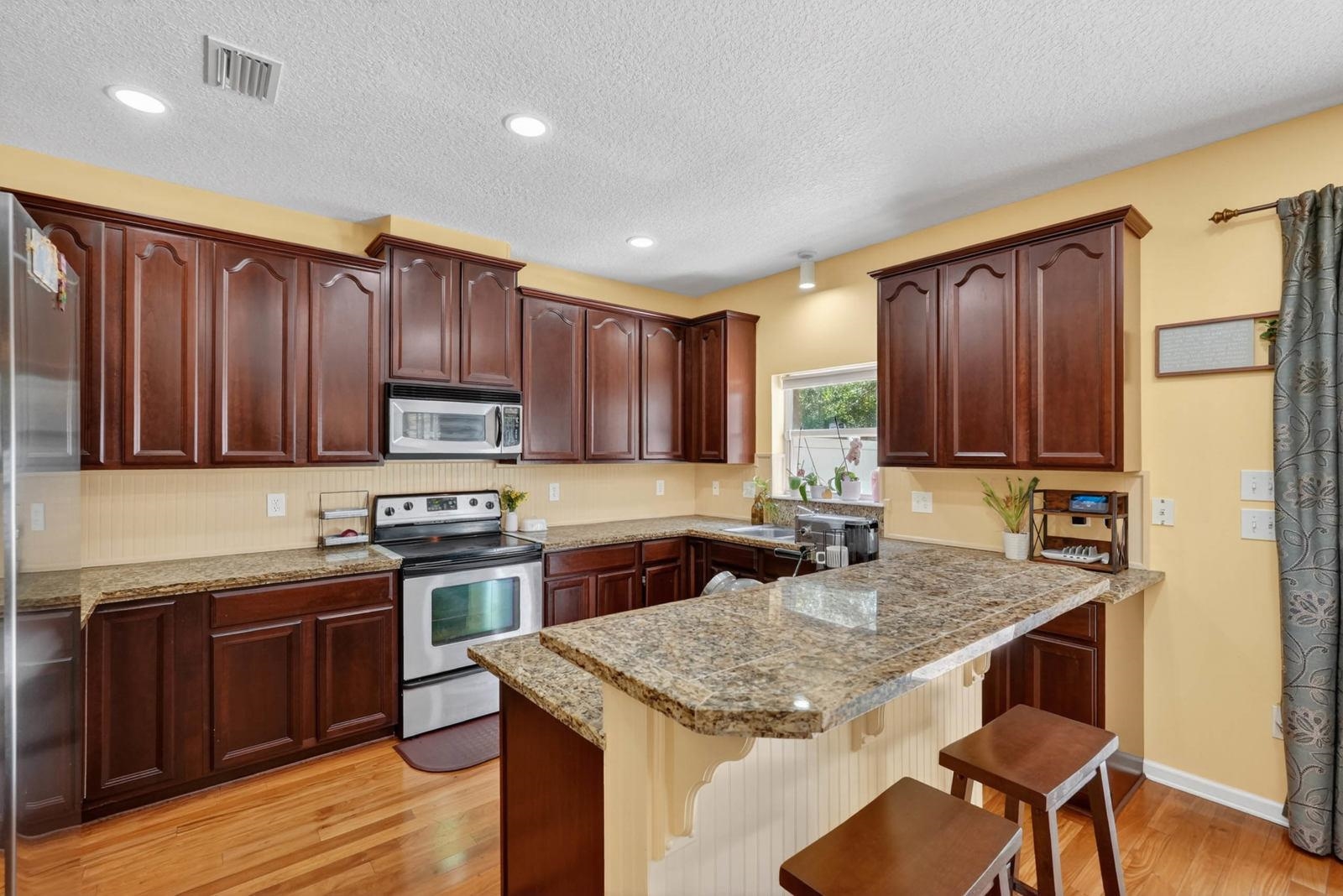 1237 Splendid Ravine Street St. Augustine, FL 32092 - Photo 13 of 62 a kitchen with stainless steel appliances granite countertop wooden cabinets a stove top oven and granite counter tops