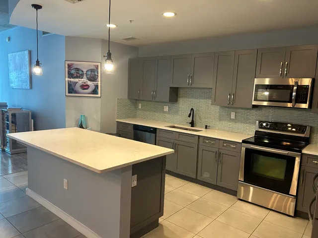 a large kitchen with cabinets chairs and refrigerator