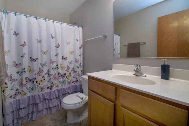 a bathroom with a granite countertop toilet sink and mirror