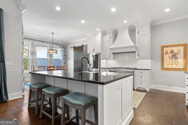 a kitchen with kitchen island granite countertop a table chairs sink and cabinets
