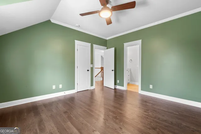 an empty room with wooden floor and a ceiling fan