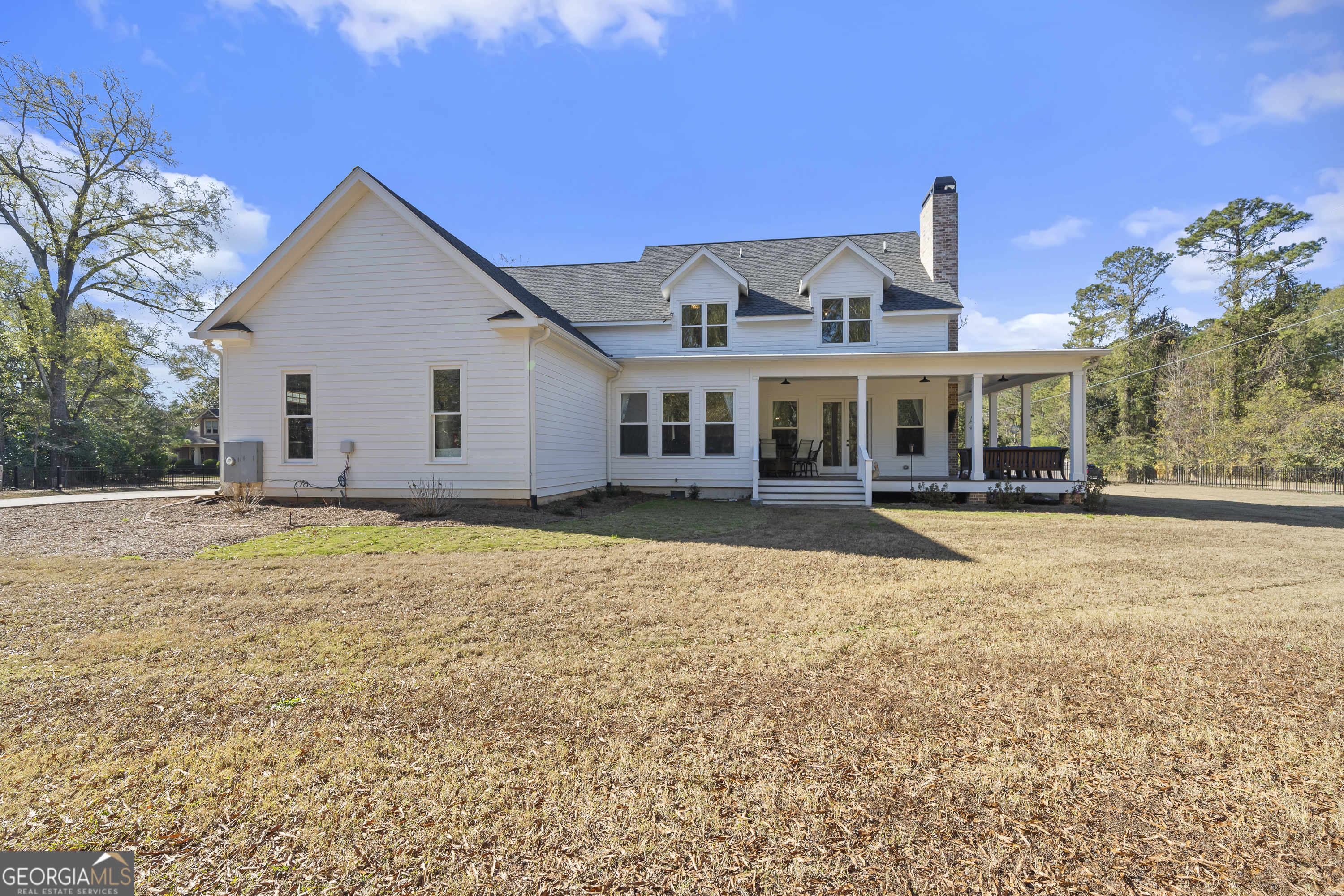 855 Jasper Street Madison, GA 30650 - Photo 43 of 46 a view of a white house with a large pool and lawn chairs under an umbrella