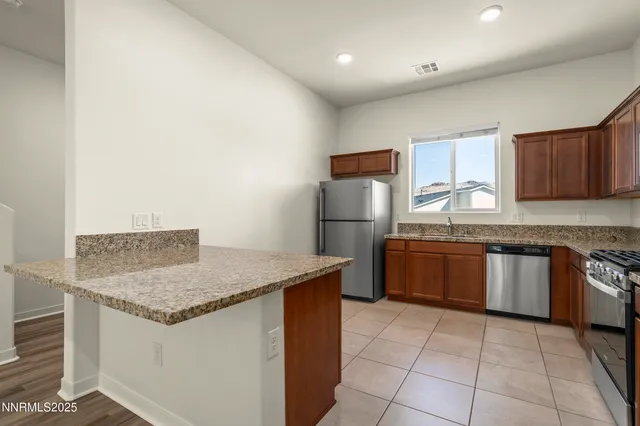 a kitchen with stainless steel appliances granite countertop wooden cabinets a stove top oven a sink and dishwasher