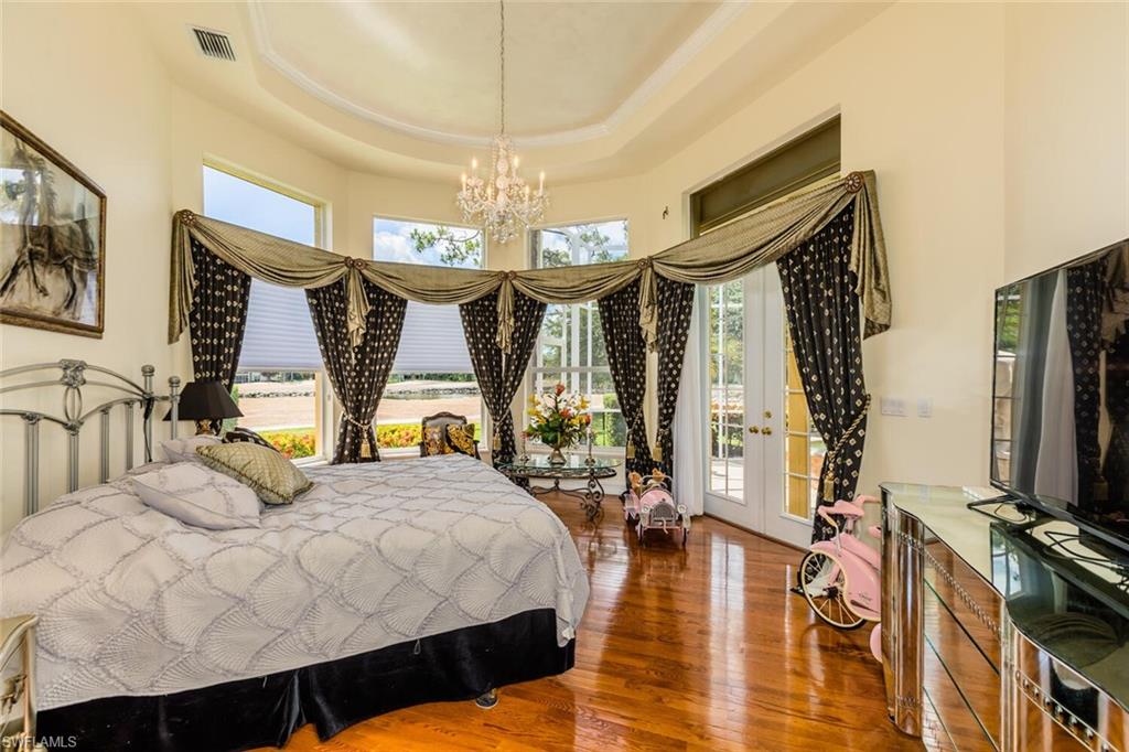 7025 Kiwi Place Naples, FL 34113 - Photo 11 of 28 a bedroom with a bed a flat screen tv and a large window