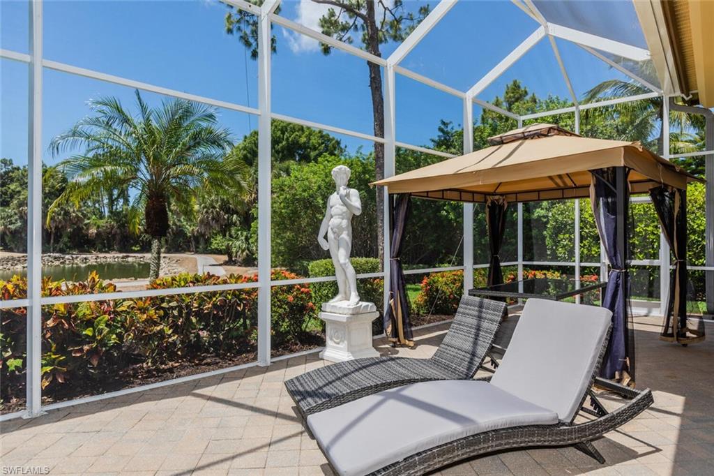 7025 Kiwi Place Naples, FL 34113 - Photo 23 of 28 a view of a patio with couches table and chairs under an umbrella