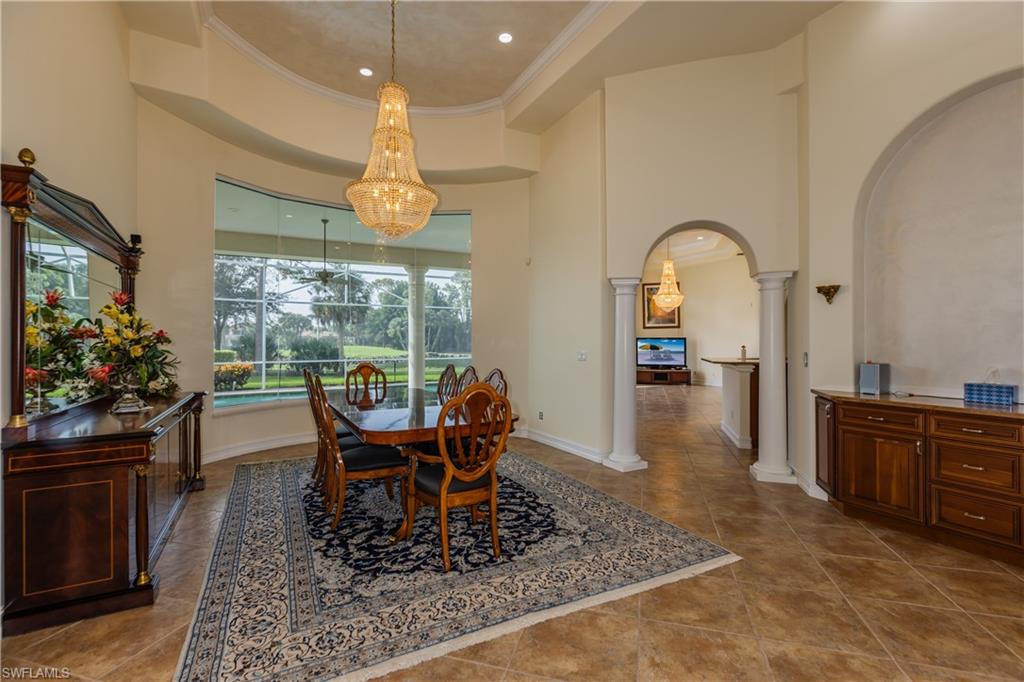 7025 Kiwi Place Naples, FL 34113 - Photo 4 of 28 a dining room with wooden floor a chandelier a wooden table and chairs