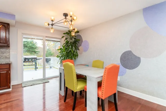 a kitchen with stainless steel appliances granite countertop a stove top oven a sink a dining table and chairs with wooden floor