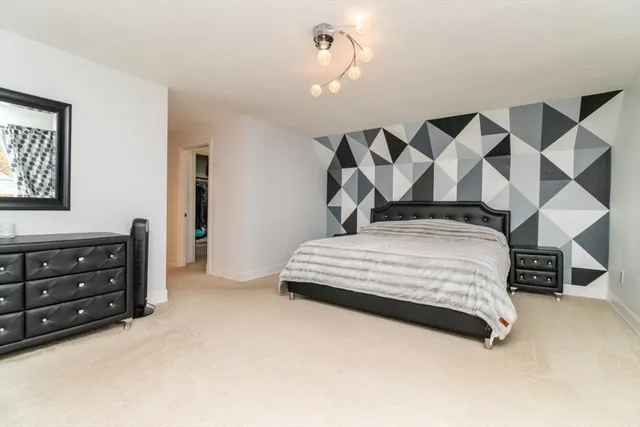 a bedroom with a bed large mirror and a chandelier