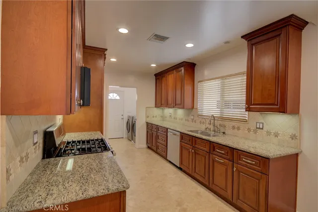 a kitchen with stainless steel appliances granite countertop a stove a sink and a refrigerator