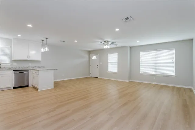 a view of an empty room with a kitchen and a window