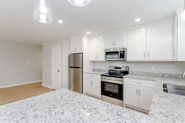 a kitchen with granite countertop white cabinets and stainless steel appliances