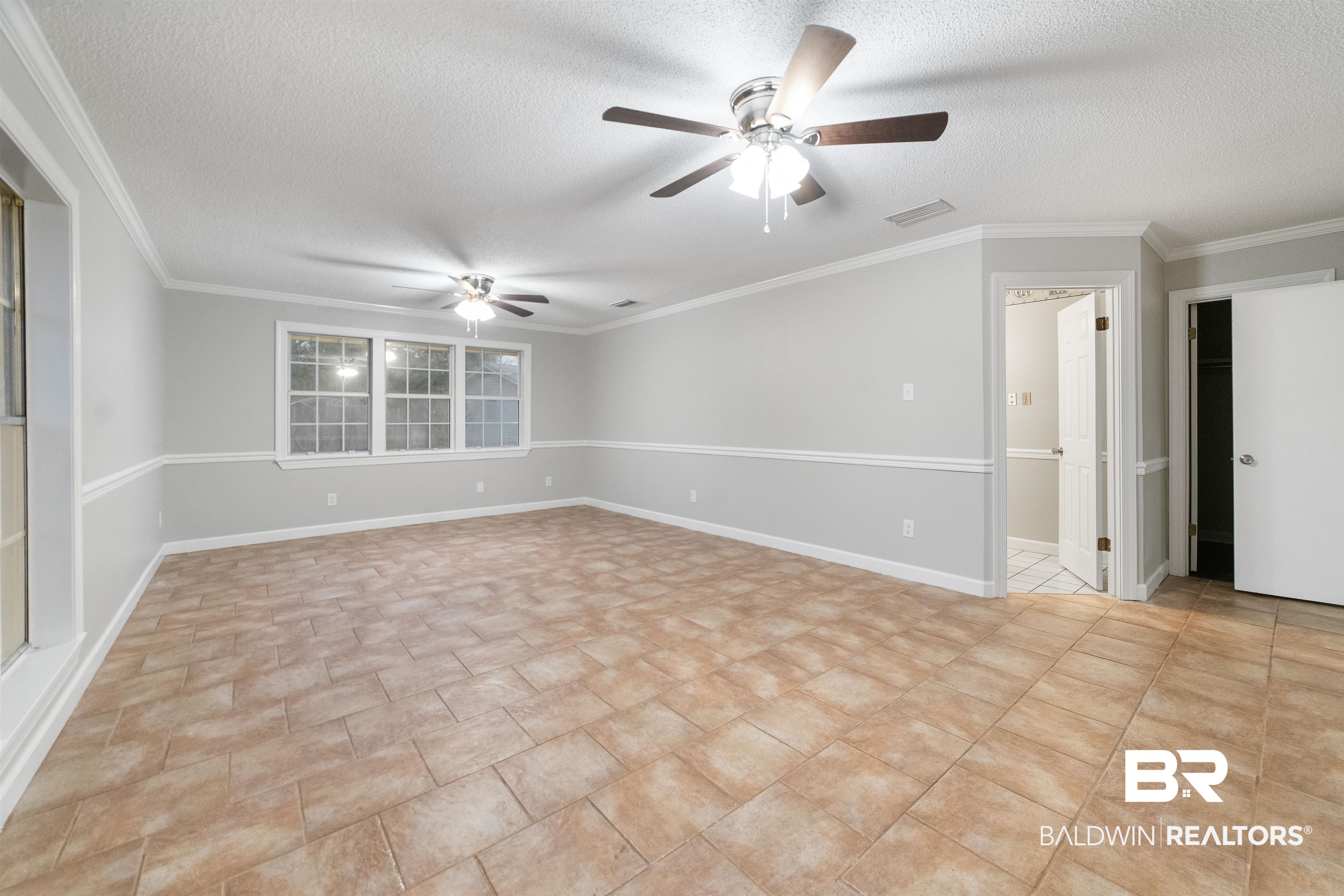11833 Old Moffat Road Wilmer, AL 36587 - Photo 7 of 23 Empty room with ornamental molding, a textured ceiling, baseboards, and a ceiling fan