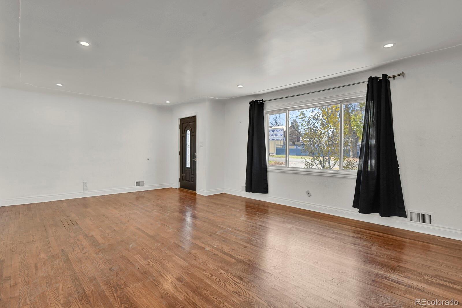 3720 Miller Street Wheat Ridge, CO 80033 - Photo 3 of 17 a view of an empty room with wooden floor and a window