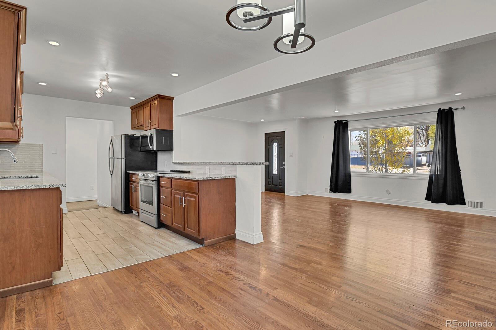 3720 Miller Street Wheat Ridge, CO 80033 - Photo 6 of 17 a kitchen with stainless steel appliances granite countertop a sink a stove top oven and a wooden floor
