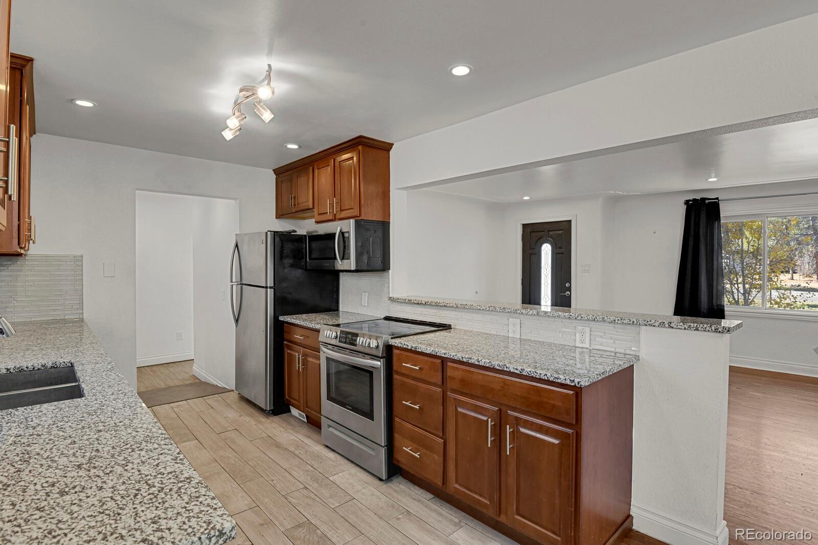 3720 Miller Street Wheat Ridge, CO 80033 - Photo 8 of 17 a kitchen with stainless steel appliances granite countertop a stove and a refrigerator