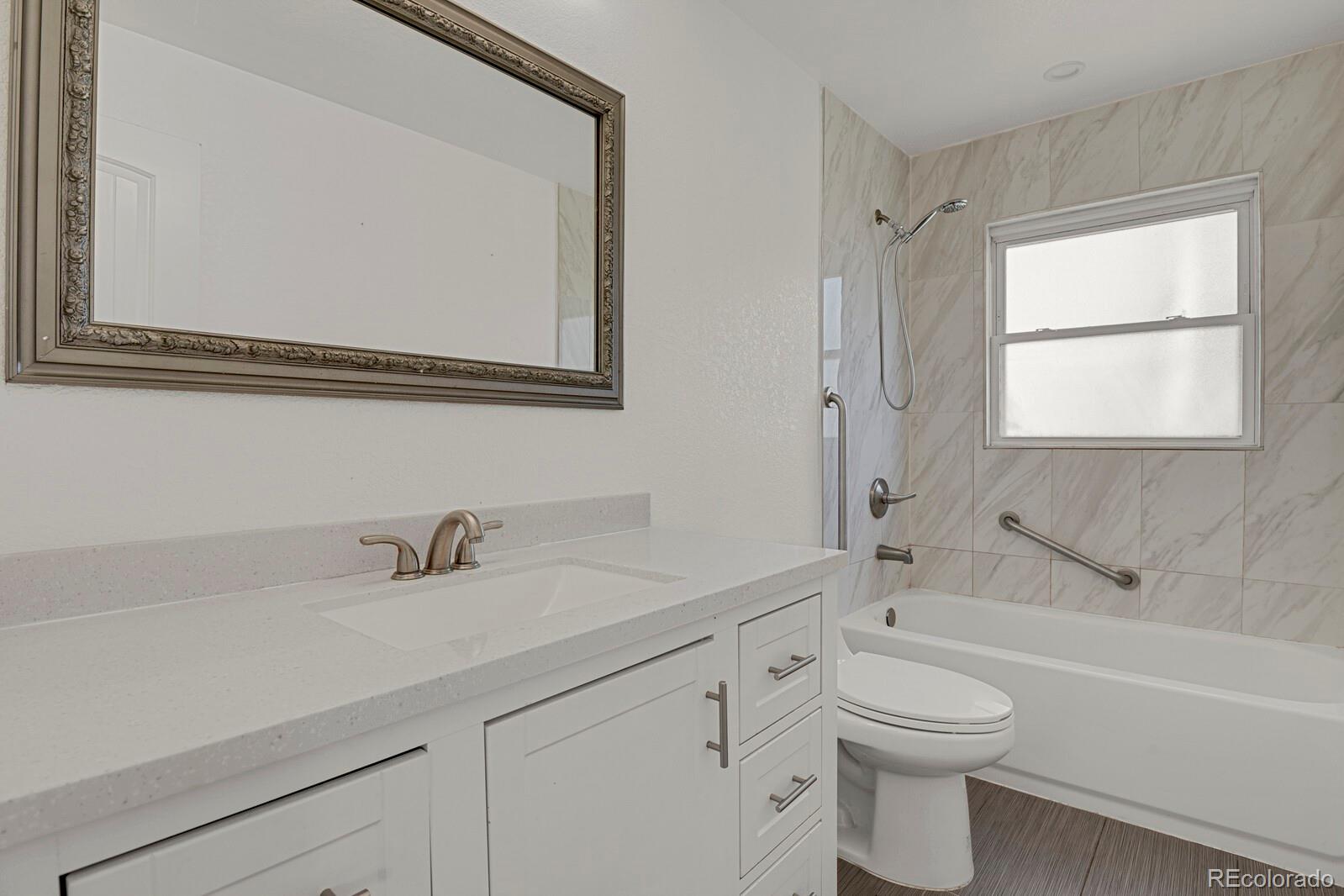 3720 Miller Street Wheat Ridge, CO 80033 - Photo 10 of 17 a bathroom with a toilet a sink a mirror and a bathtub