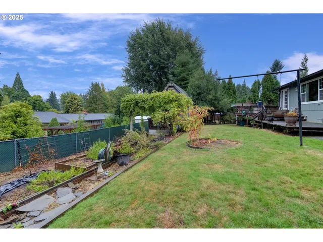 a backyard of a house with table and chairs plants and large tree