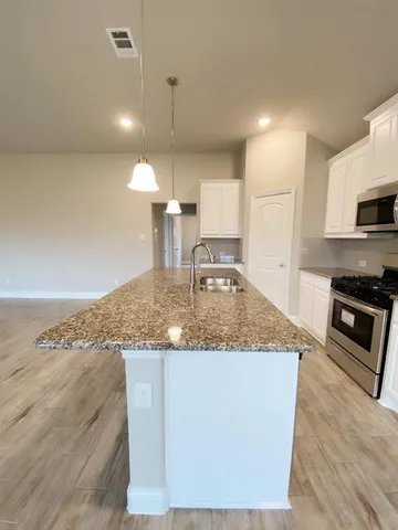 an empty room with a chandelier fan and windows