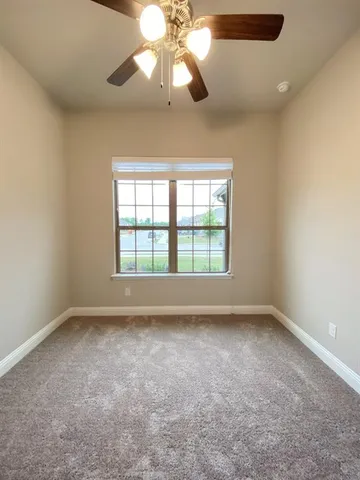 a view of empty room with wooden floor and ceiling fan