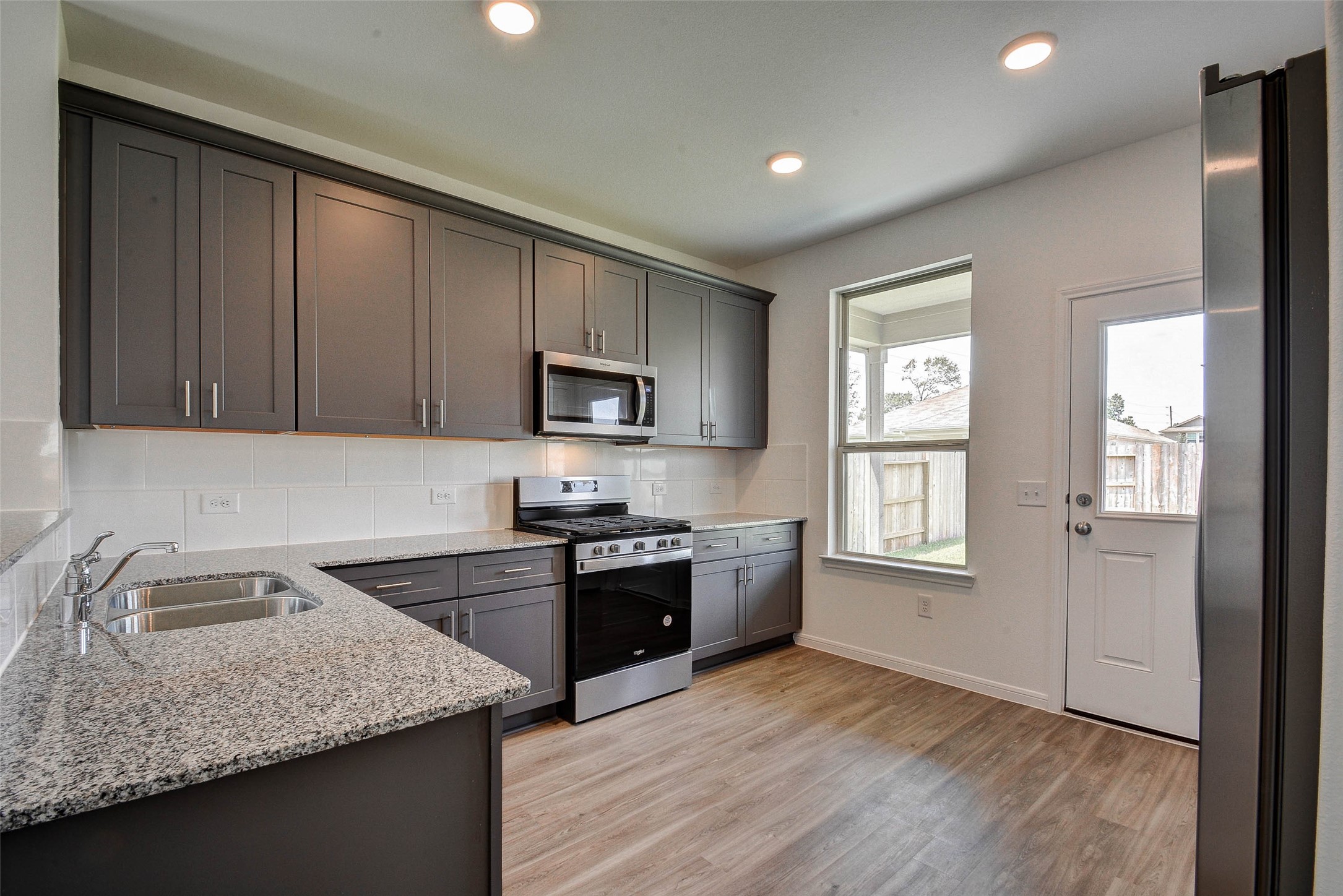 16642 Teak Mantle Road Conroe, TX 77302 - Photo 12 of 35 a kitchen with granite countertop stainless steel appliances sink stove microwave and refrigerator