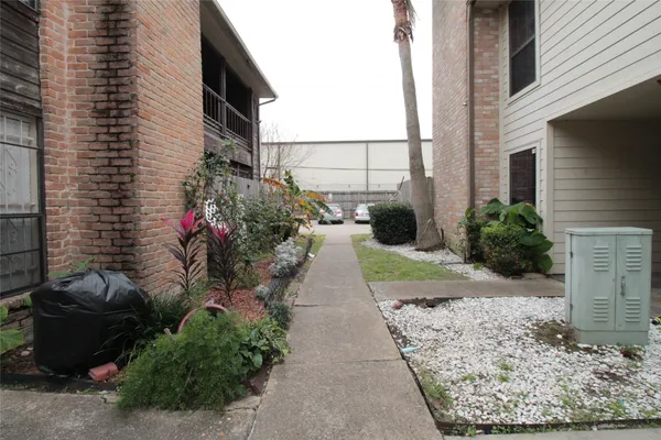 a view of a pathway that has a bunch of flower plants in front of house